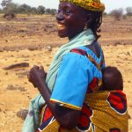 Niger, donna con bambino sulle spalle lungo la strada verso Abalak