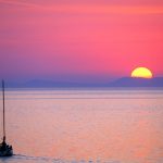 Croazia isola di Pag, una barca a vela salpa al tramonto dal porticciolo di Mandre