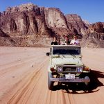 giordania, wadi rum, a jeep travels with tourists for an excursion in the desert
